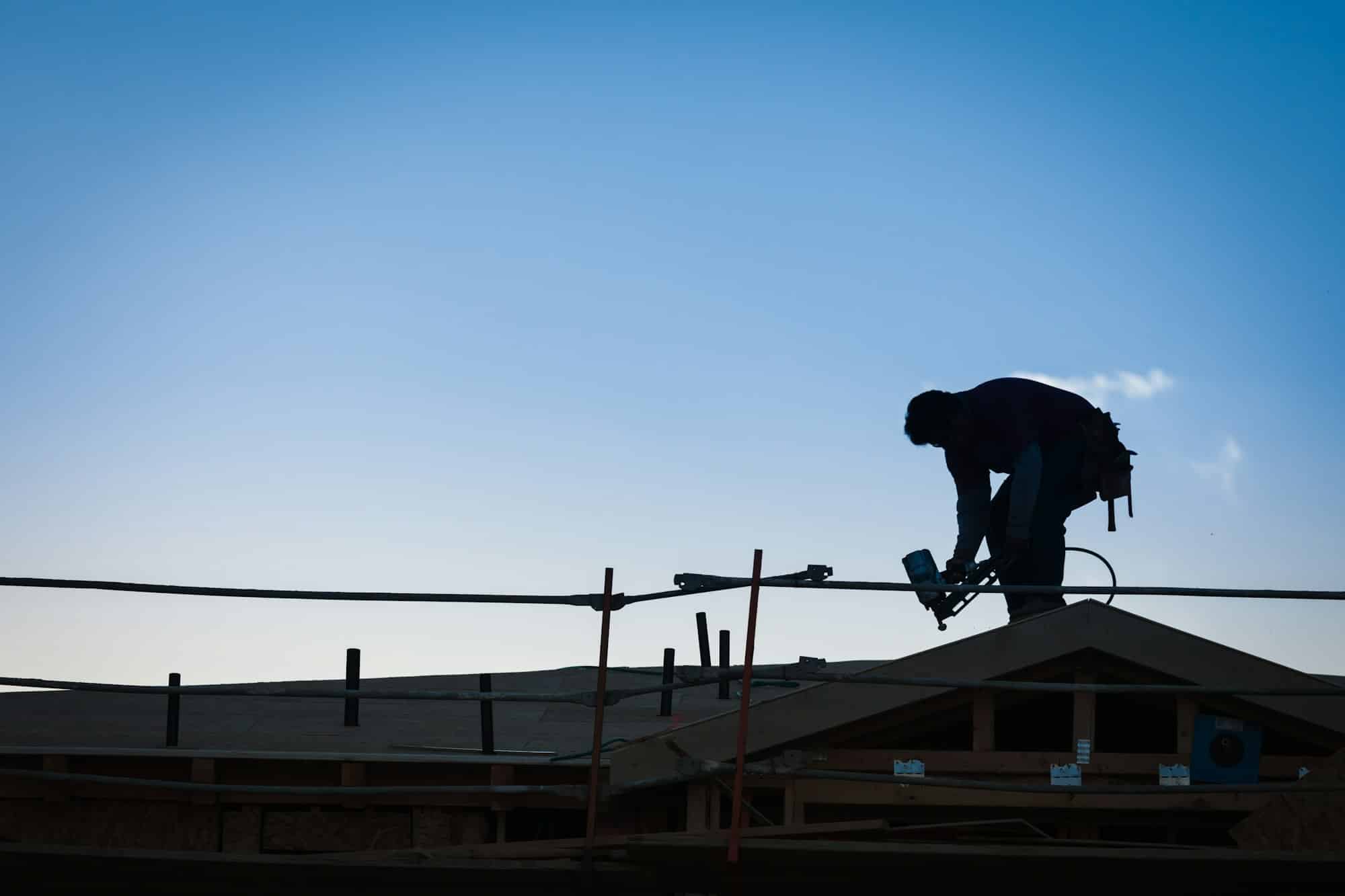 Construction Workers Silhouette on Roof of Building