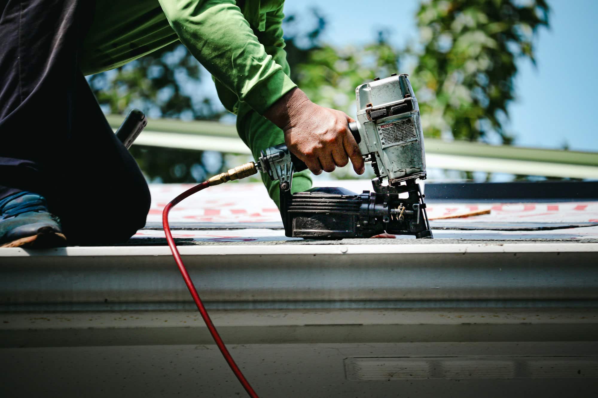 Man using a nail gun on the roof