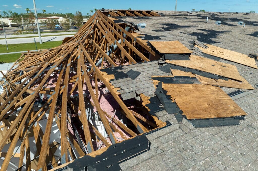 Consequences of natural disaster. Damaged house roof with missing shingles