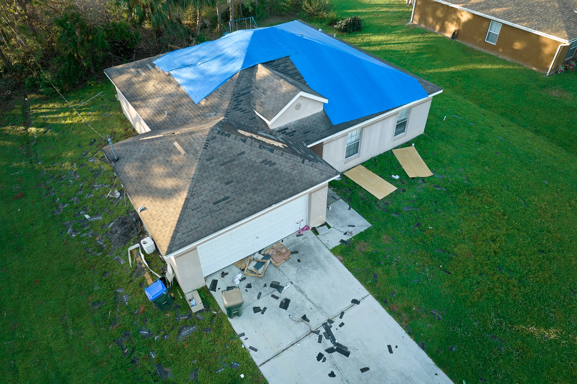 Top view of leaking house roof covered with protective tarp sheets against rain water